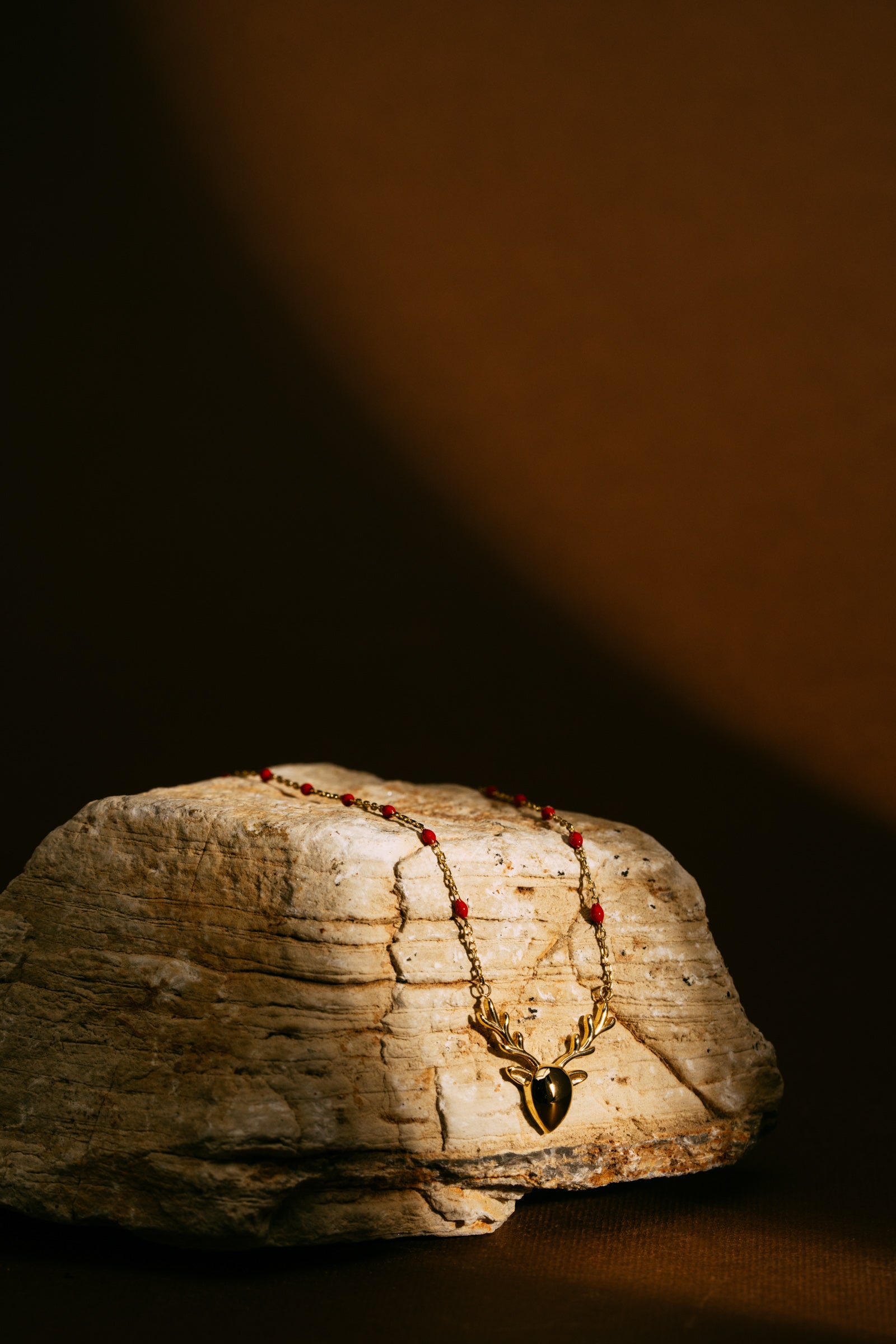 Collar de oro con colgante sobre una piedra | Mua Mua Jewels
