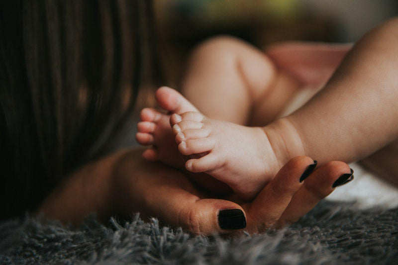 Pies de un bebé en la mano de su madre